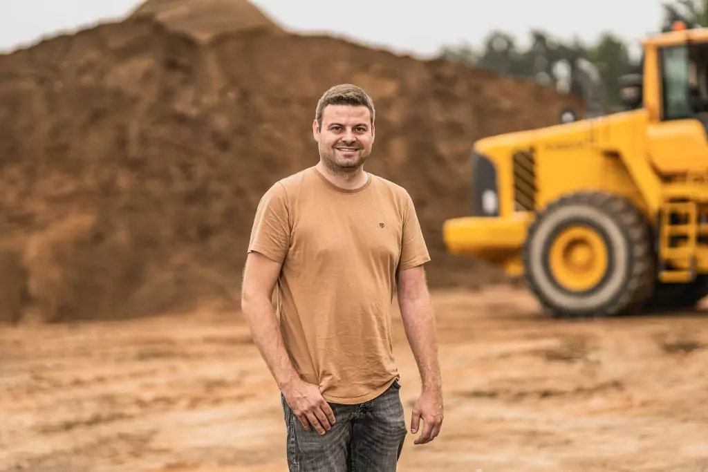 Tim Dotterweich, Juniorchef des Familienunternehmens, auf dem Betriebsgelände mit Sandlager und Radlader im Hintergrund