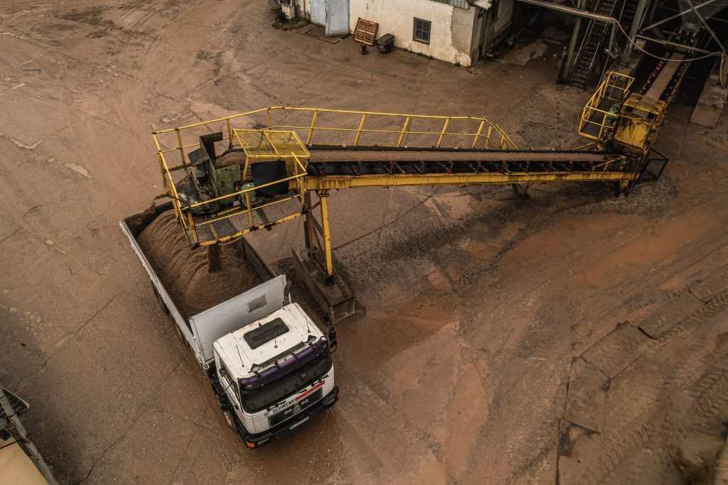Beladung eines Lkw mit Sand über eine industrielle Förderbandanlage